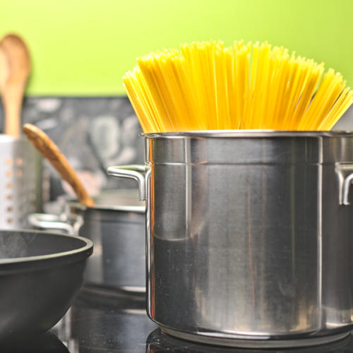 TwooDoo - Edelstahltopf mit Spaghetti neben gusseiserner Pfanne.